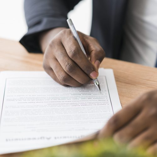 crop-ethnic-businessman-signing-papers-scaled